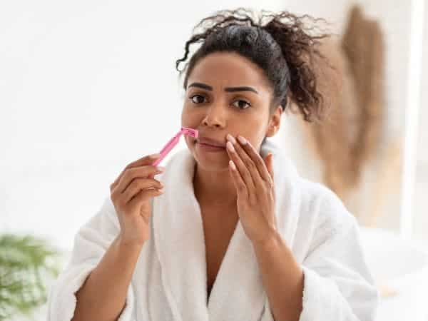 ragazza che cerca di depilare viso con rasoio